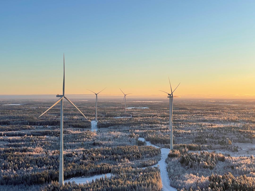 4 windturbines in the forest while sunset