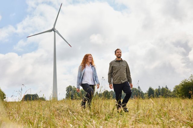 Two people go for a walk near a wind farm