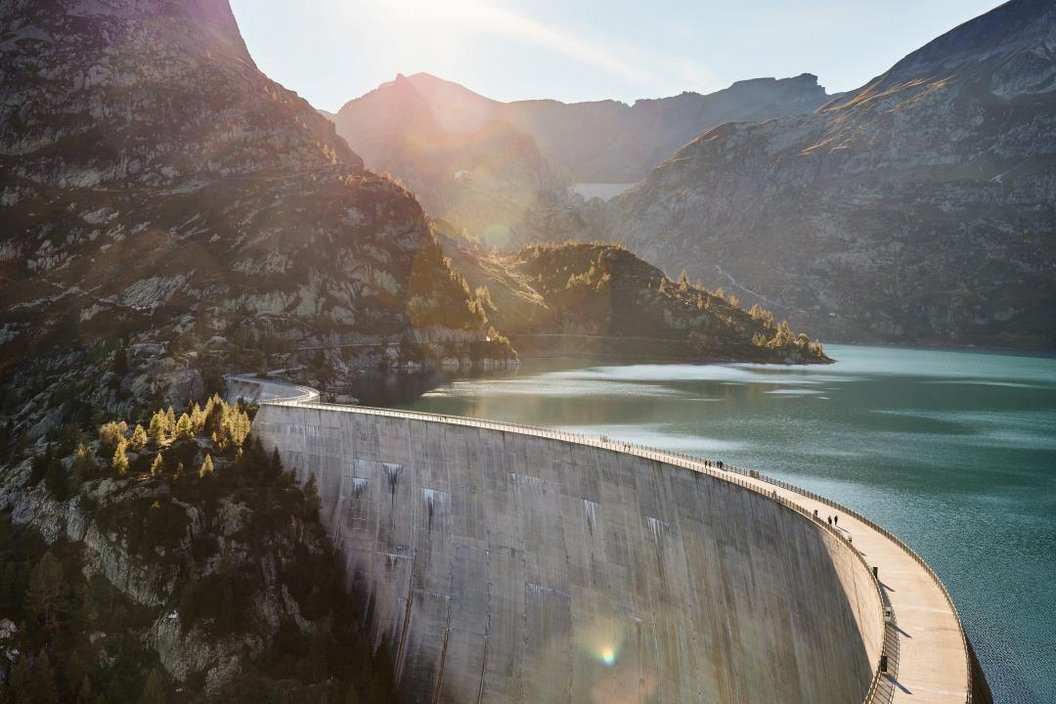 While the sun is starting to set it shines over the mountains on the Emosson Lake with a damn splitting the image in 2