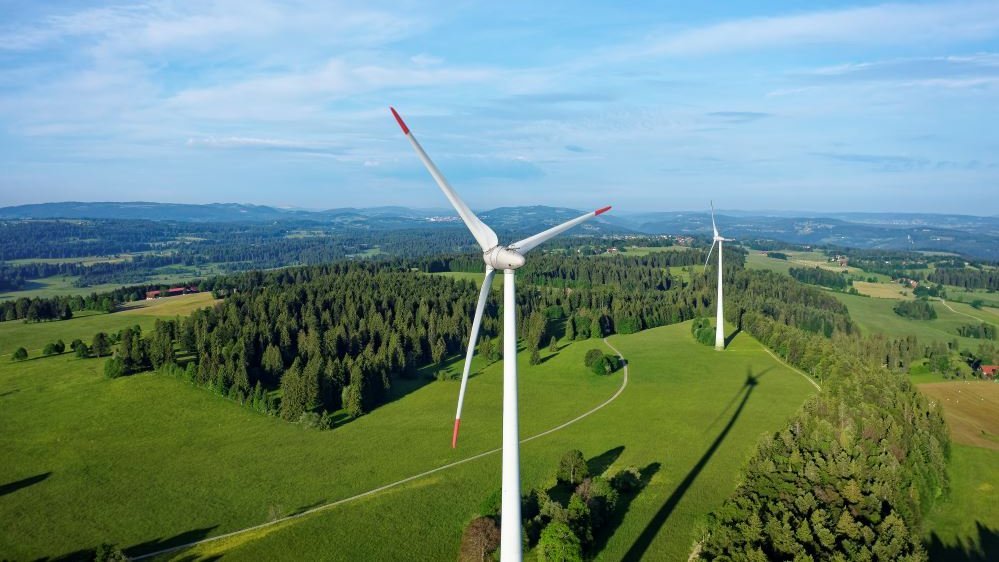 a green hill with some wind turbines on it and blue sky