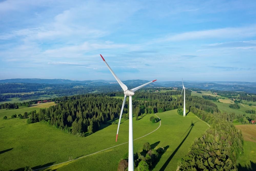 a green hill with some wind turbines on it and blue sky